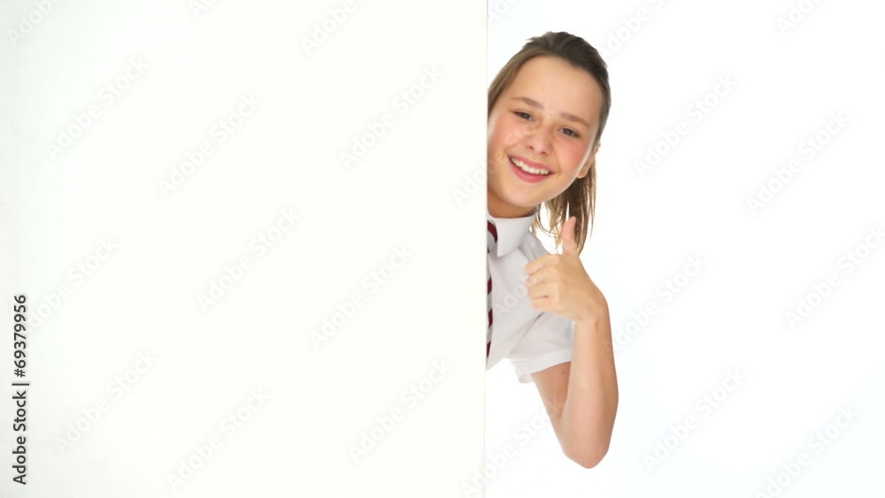 Young girl peering around the edge of a sign