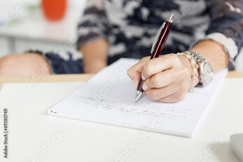 Hand (Frau) schreibend mit Kugelschreiber und Notizblock photo