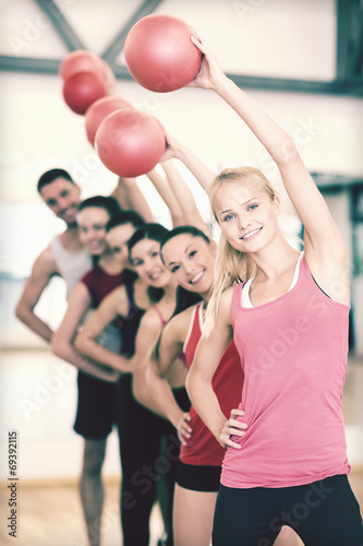 group of smiling people working out with ball