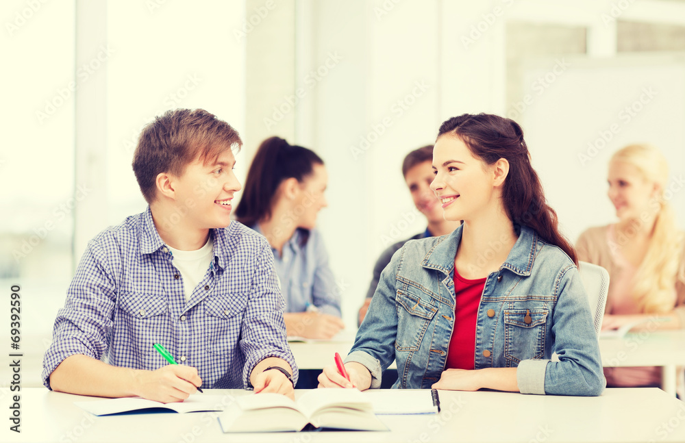 two teenagers with notebooks and book at school two teenagers with notebooks and book at school