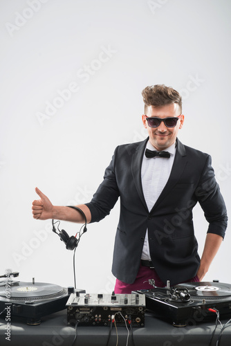 DJ in tuxedo showing his thumb up standing by turntable