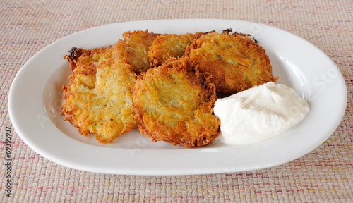 Potato pancakes with sour cream on a plate