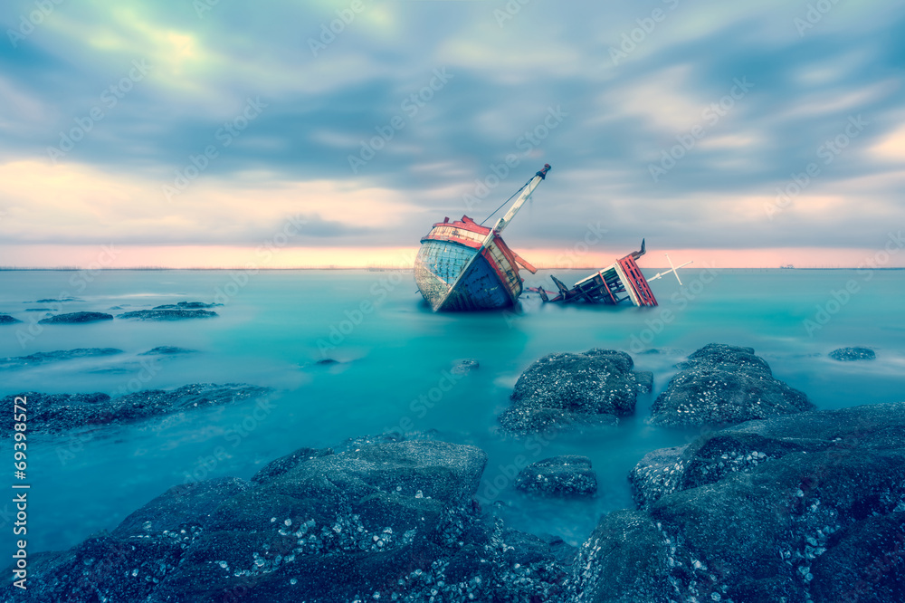 Shipwreck or wood ship broken damage on land, coast or beach with sea and sunset background. That result of accident, storm, crash, wave in ocean or marine. For assurance, travel or adventure concept. Shipwreck or wood ship broken damage on land, coast or beach with sea and sunset background. That result of accident, storm, crash, wave in ocean or marine. For assurance, travel or adventure concept.
