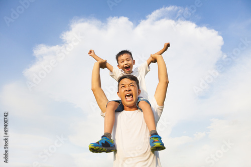 happy little boy sitting on father's shoulder