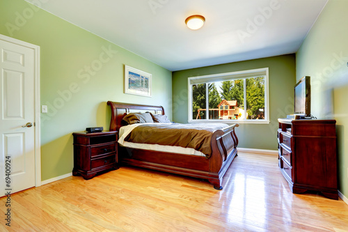 Green bedroom with carved wood furniture