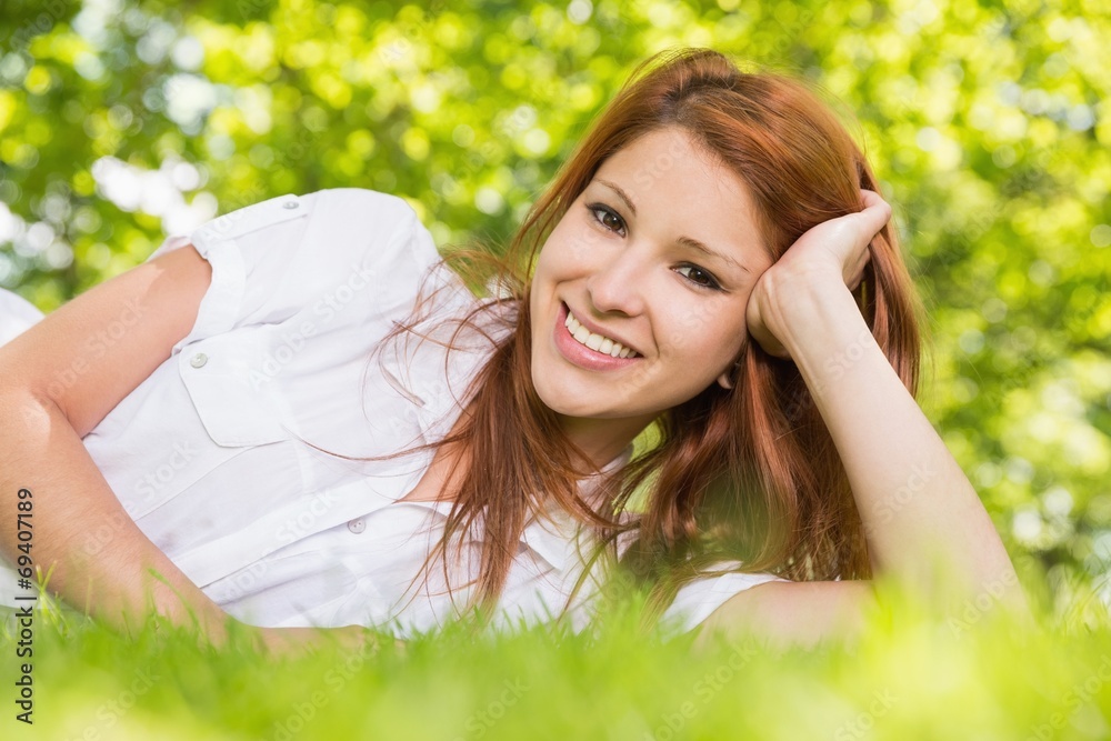 Pretty redhead lying on the grass smiling at camera Pretty redhead lying on the grass smiling at camera