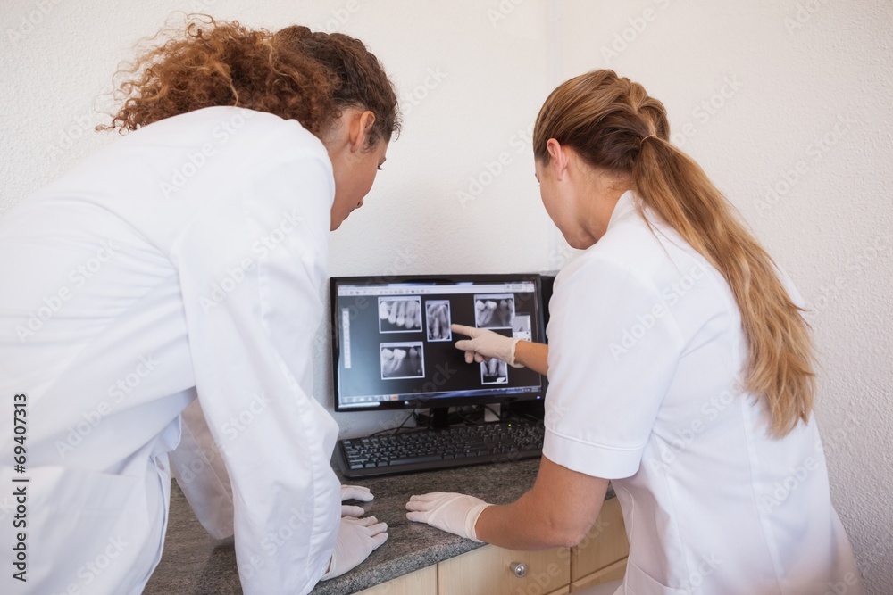Dentist and assistant studying x-rays on computer Dentist and assistant studying x-rays on computer