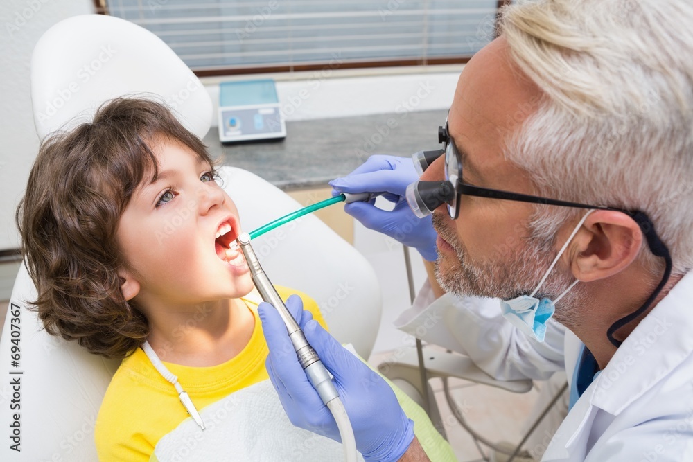 Pediatric dentist examining a boys teeth Pediatric dentist examining a boys teeth