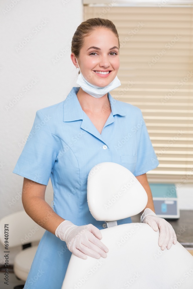 Dental assistant smiling at camera beside chair