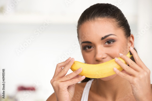 creative portrait of woman holding yellow banana in her hand.