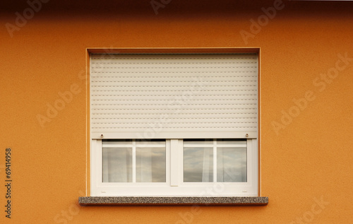 Modernes Kunststofffenster mit halb geschlossenem Rollladen photo