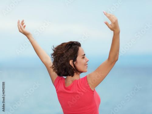 Beautiful young woman enjoying summer with her arms outstretched