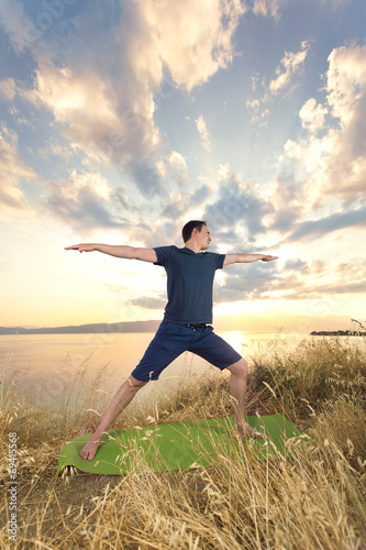 Young man practicing yoga in nature at sunset.