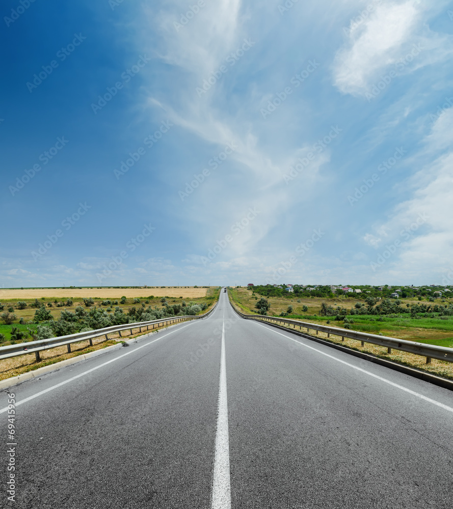 white line on asphalt road and clouds in sky over it