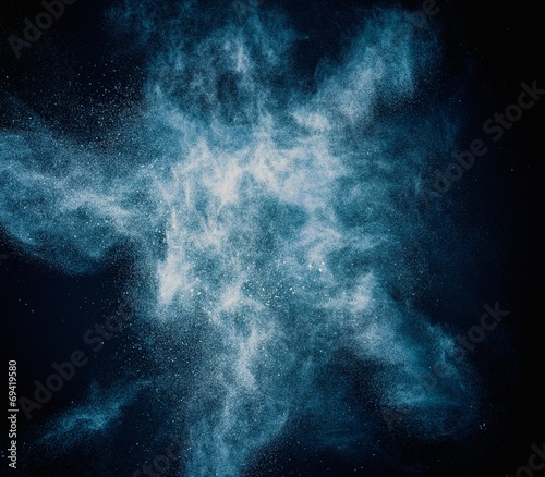 Blue powder exploding isolated on black