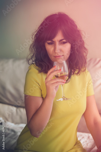 Thoughtful young woman smelling a glass of wine, the morning aft