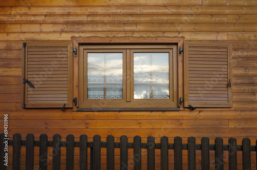 Fenster aus Holzimitat mit Klappläden in Holzfassade photo