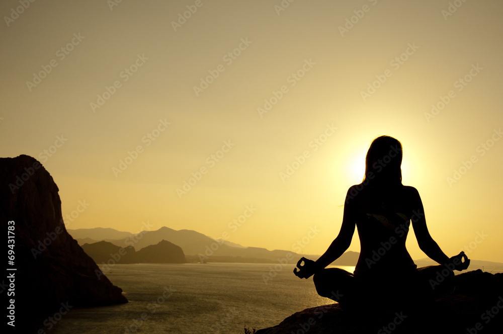 Yoga lotus position silhouette on seaside at sunrise