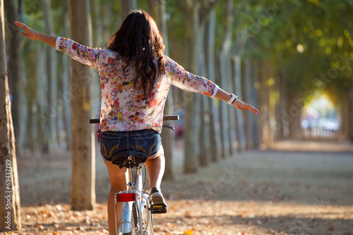 Pretty young girl riding bike in a forest.