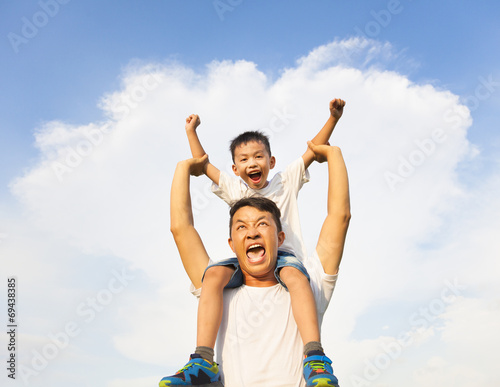 happy little boy sitting on father's shoulder