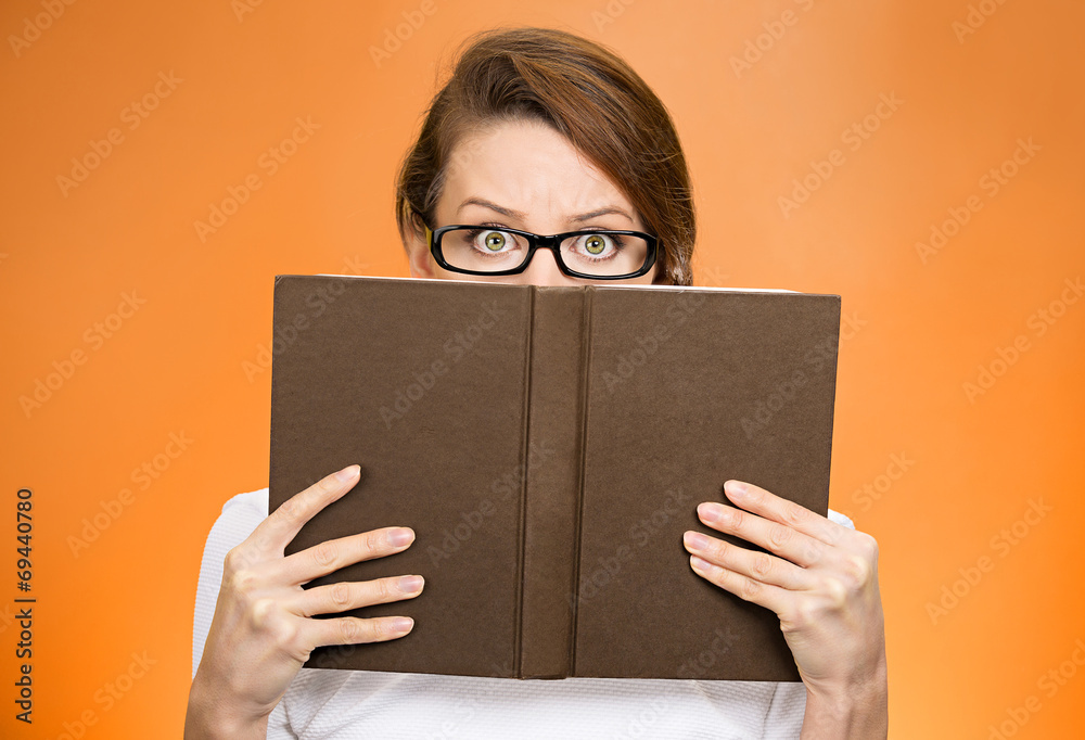 Woman with glasses hiding her face behind book Woman with glasses hiding her face behind book