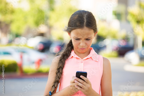 Unhappy girl reading text message on smart mobile phone