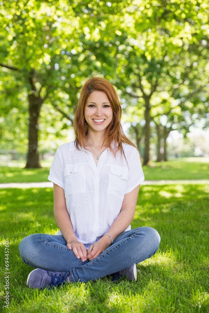 Pretty redhead smiling at camera in the park Pretty redhead smiling at camera in the park