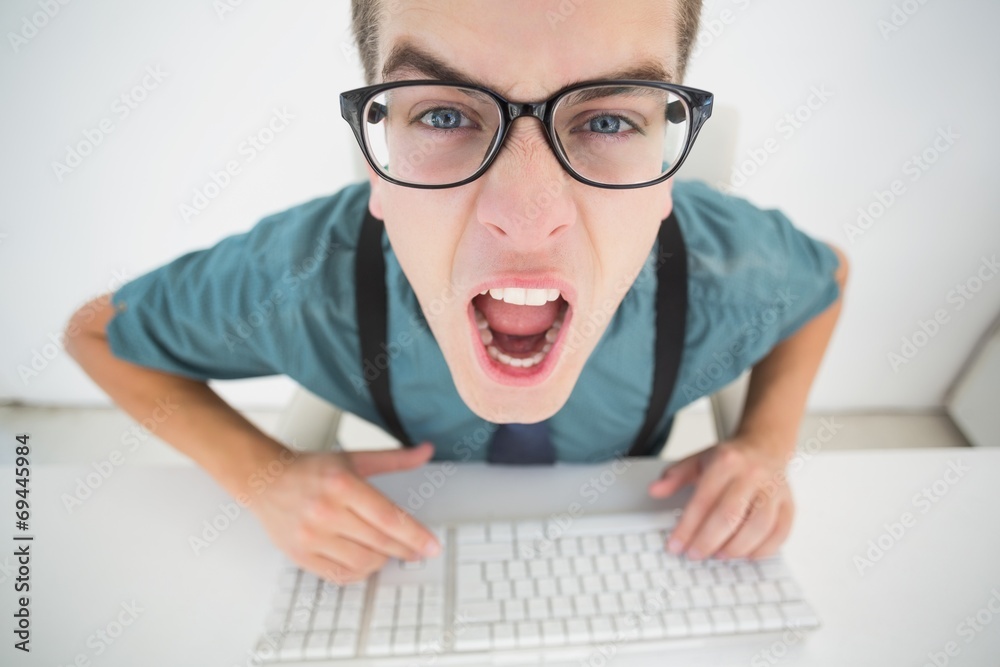 Casual angry businessman typing at his desk Casual angry businessman typing at his desk