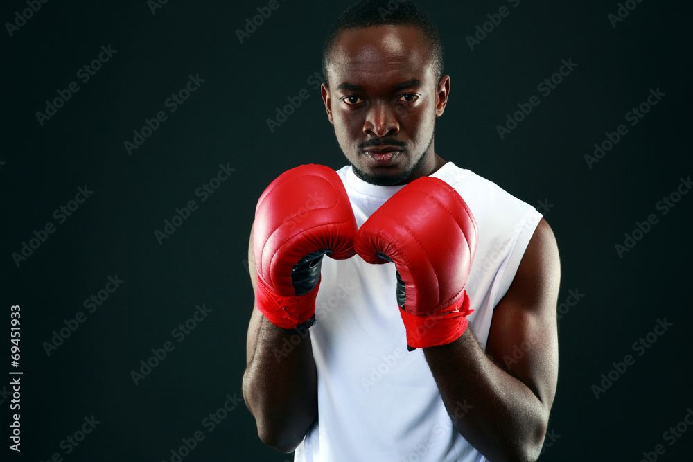 African man in boxing gloves standing over black background