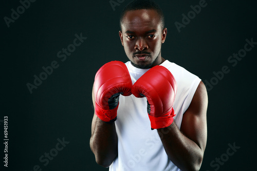 African man in boxing gloves standing over black background © Drobot Dean