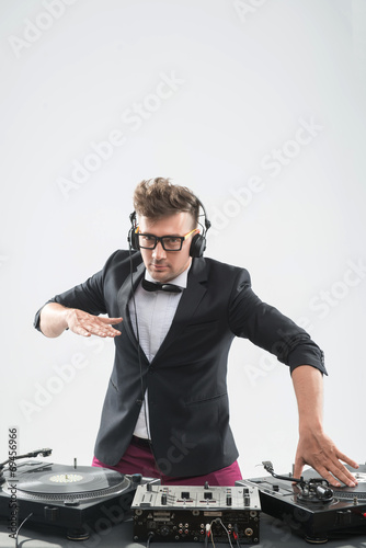 DJ in tuxedo having fun and dancing by the turntable