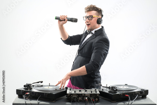 DJ in tuxedo having fun and dancing with microphone by the turnt photo