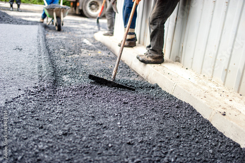 worker with special tool working with fresh asphalt and bitumen