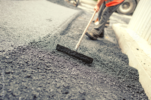 Worker levellng fresh asphalt on a road construction site