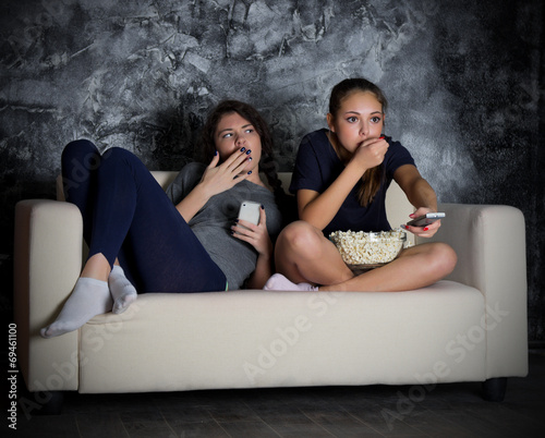 Two young girls looks TV