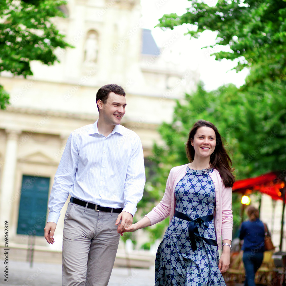 Happy positive couple walking in Paris near a street cafe