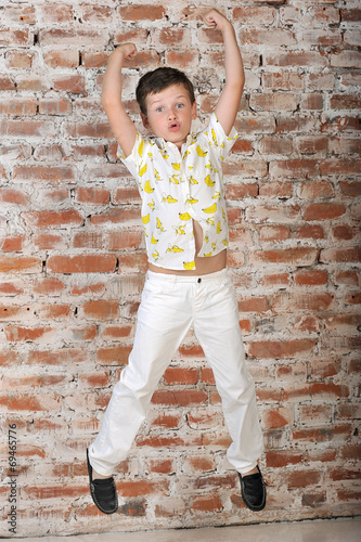 a little boy of 7 years, in a shirt with bananas, white trousers