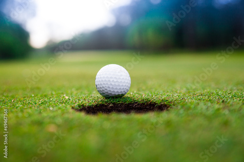 Golf ball on green meadow. golf ball on lip of cup