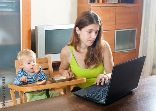 Woman working with laptop and baby photo