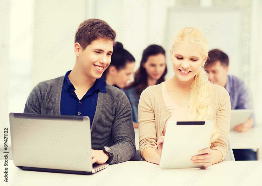 two smiling students with laptop and tablet pc two smiling students with laptop and tablet pc