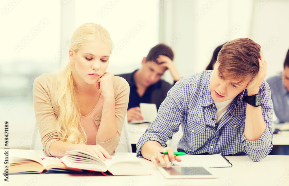 tired students with tablet pc, books and notebooks tired students with tablet pc, books and notebooks