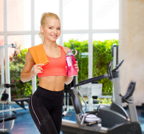 smiling sporty woman with water bottle and towel
