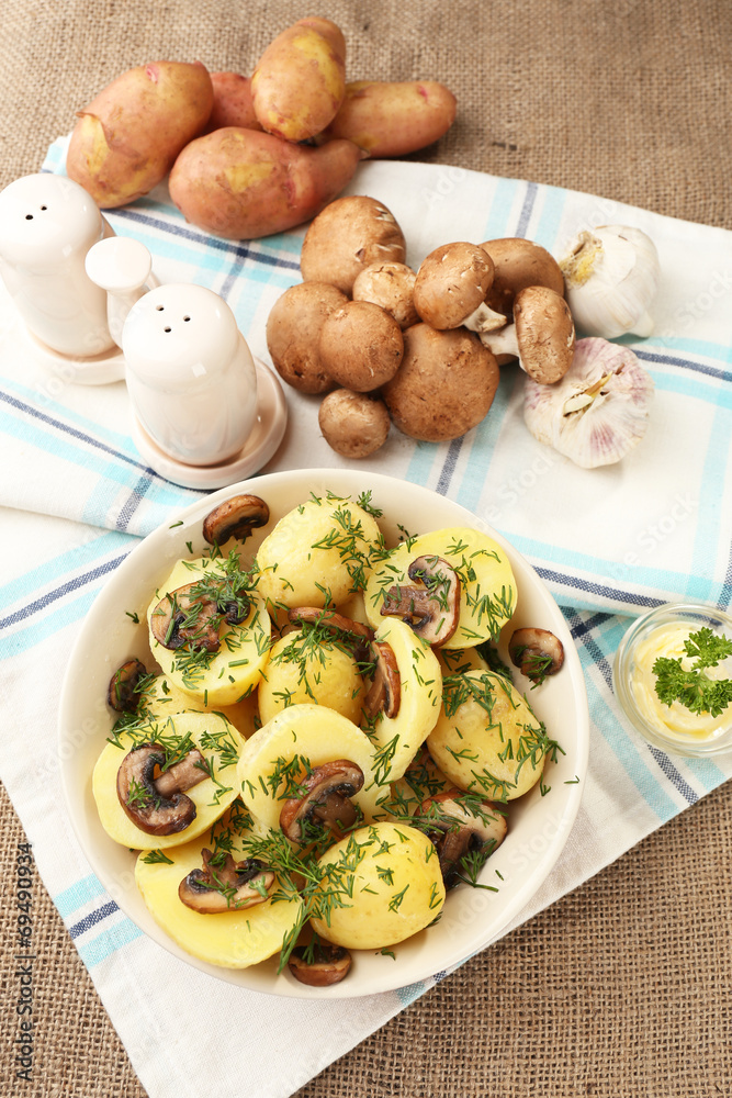 Young boiled potatoes with mushrooms on table, close up