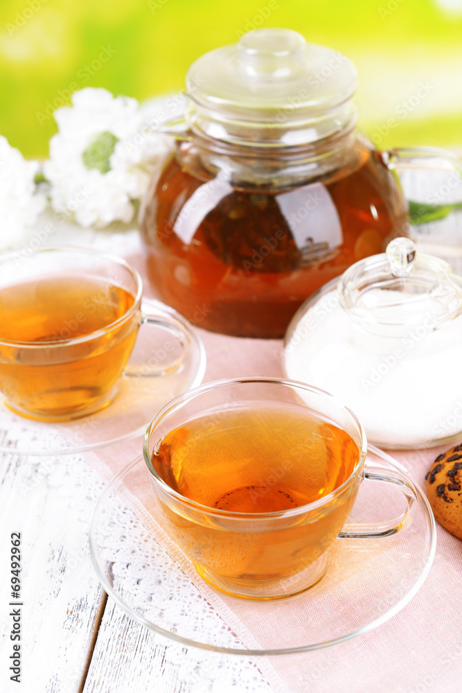 Teapot and cups of tea on table on bright background Teapot and cups of tea on table on bright background