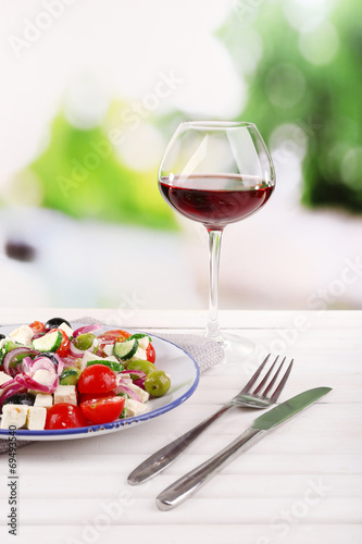 Greek salad served in plate with glass of wine