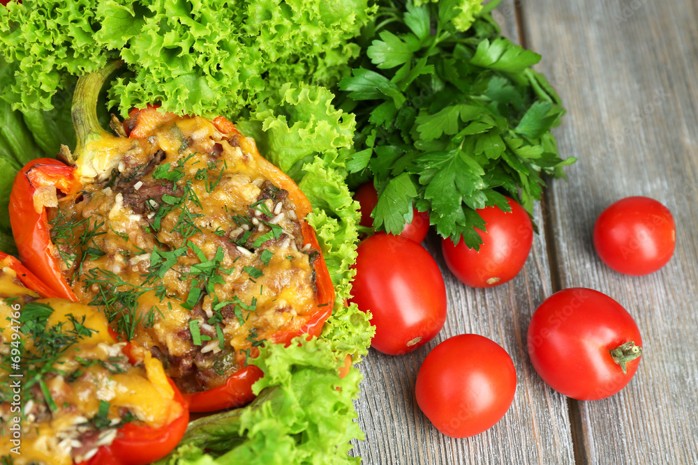Stuffed red peppers with greens and vegetables on table close Stuffed red peppers with greens and vegetables on table close