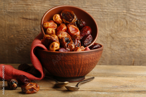 Tasty dates fruits in bowls, on wooden background