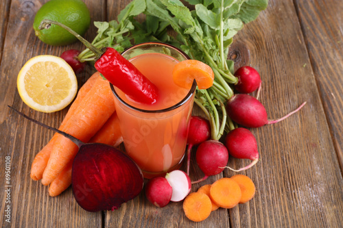 Fresh carrot juice with vegetables on wooden background