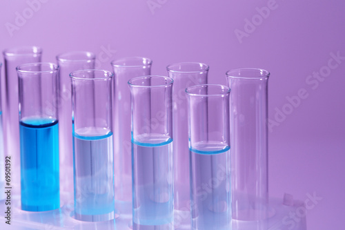 Test-tubes with blue liquid on purple background