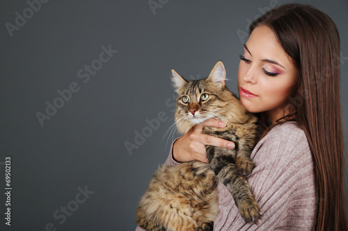 Beautiful young woman holding cat on gray background photo